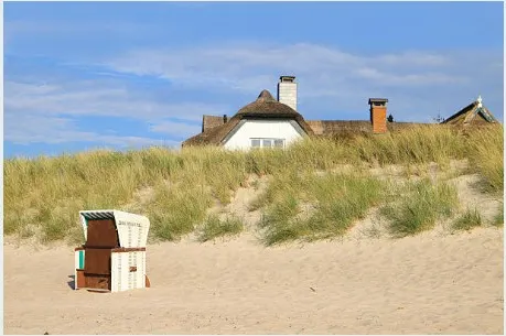 Strandkorb vor reetgedecktem Haus an der Ostsee